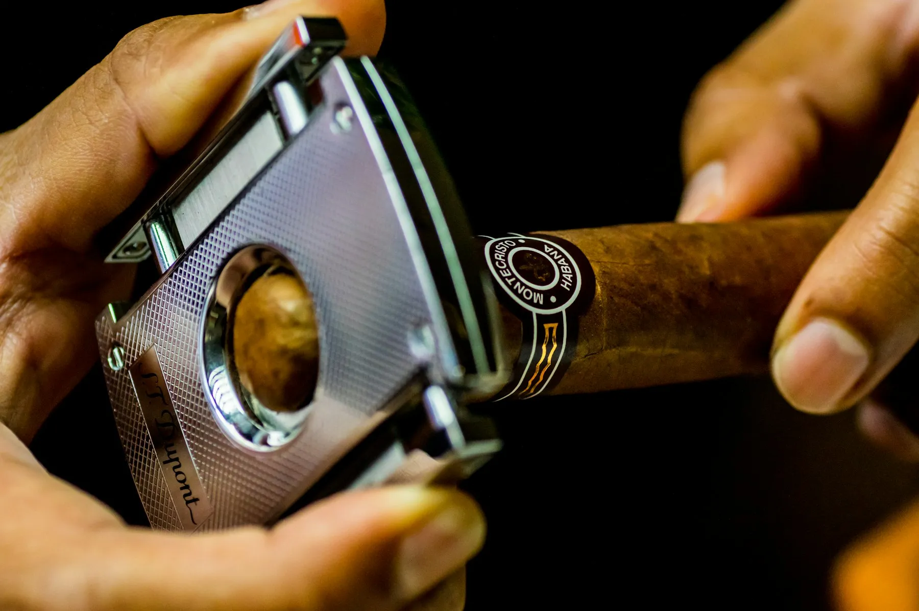 A tobacconist's hands cutting a cigar