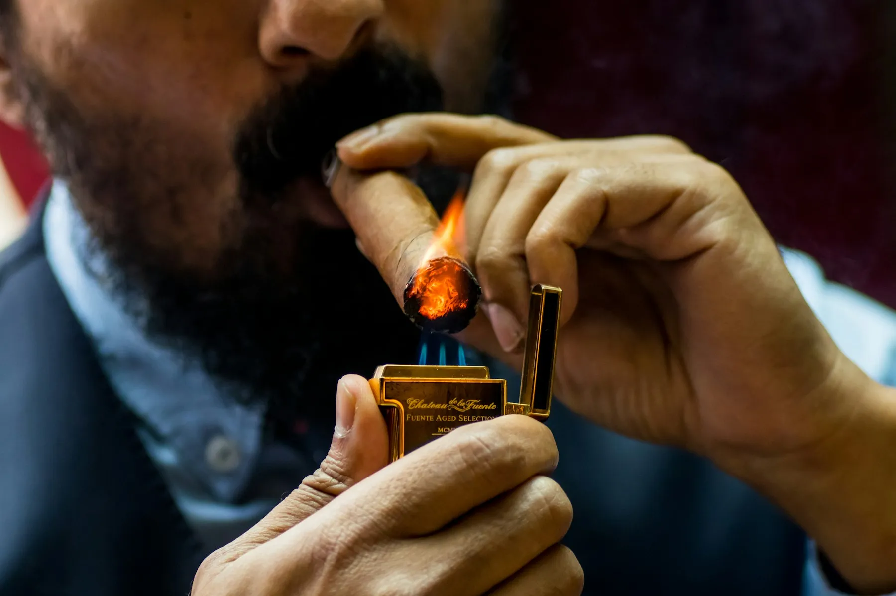 A man toasting the foot of a cigar with a match